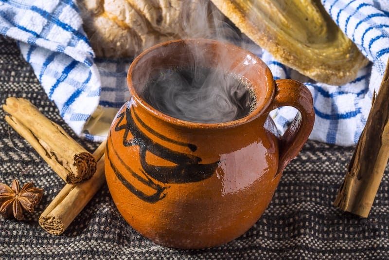 Steaming cafe de olla in a traditional clay mug with cinnamon